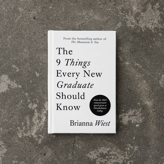 Book titled 'The 9 Things Every New Graduate Should Know' by Brianna Wiest on a textured gray surface