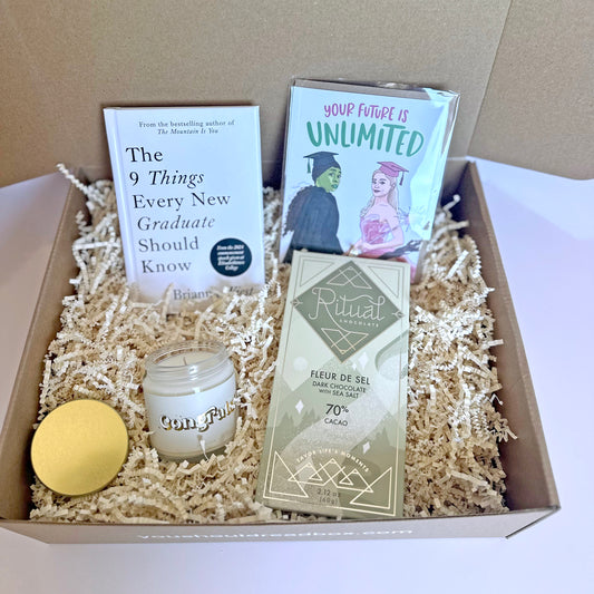 Gift box with a candle, book, chocolate bar, and books on a neutral background