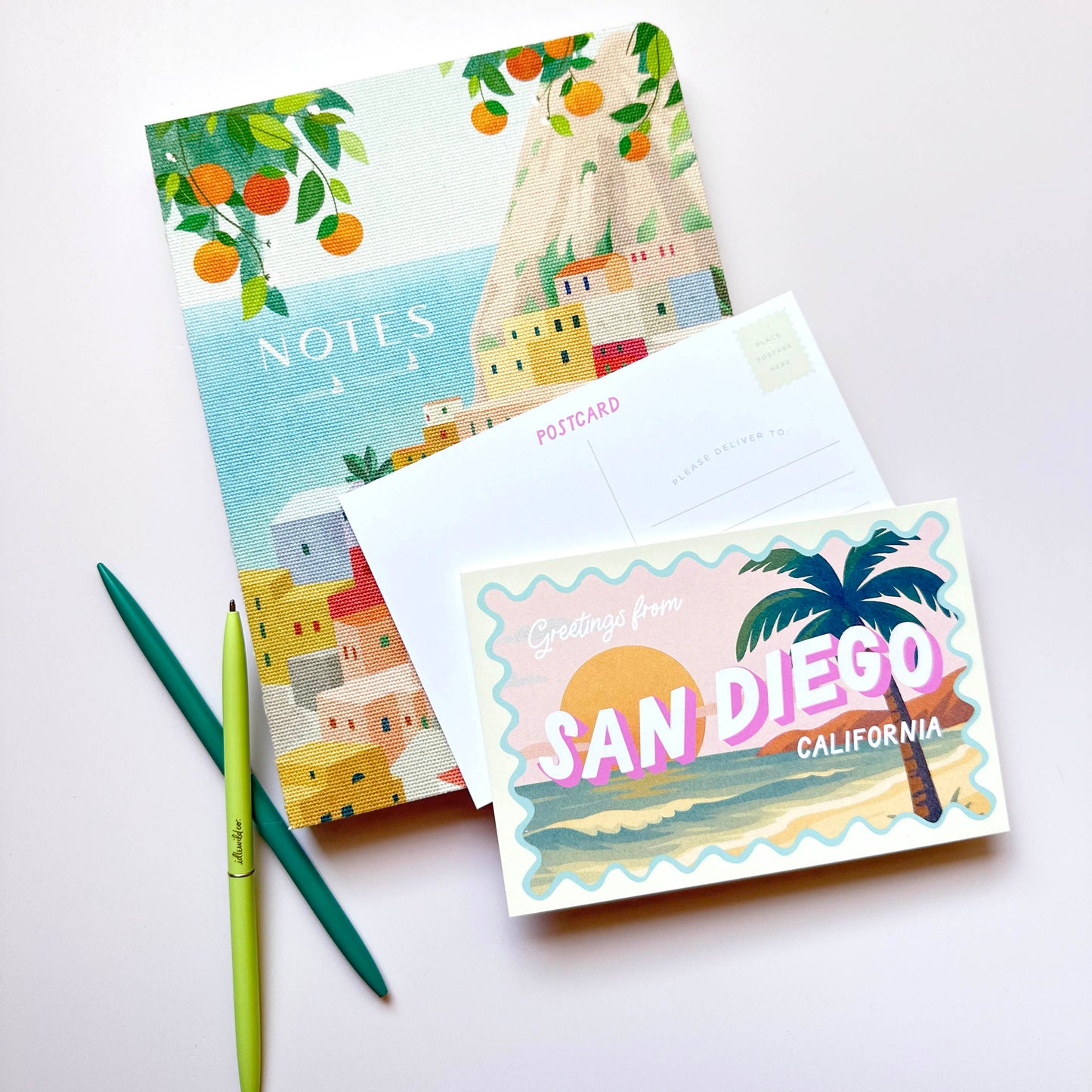 Notebook and postcard with 'Greetings from San Diego, California' design on a white background
