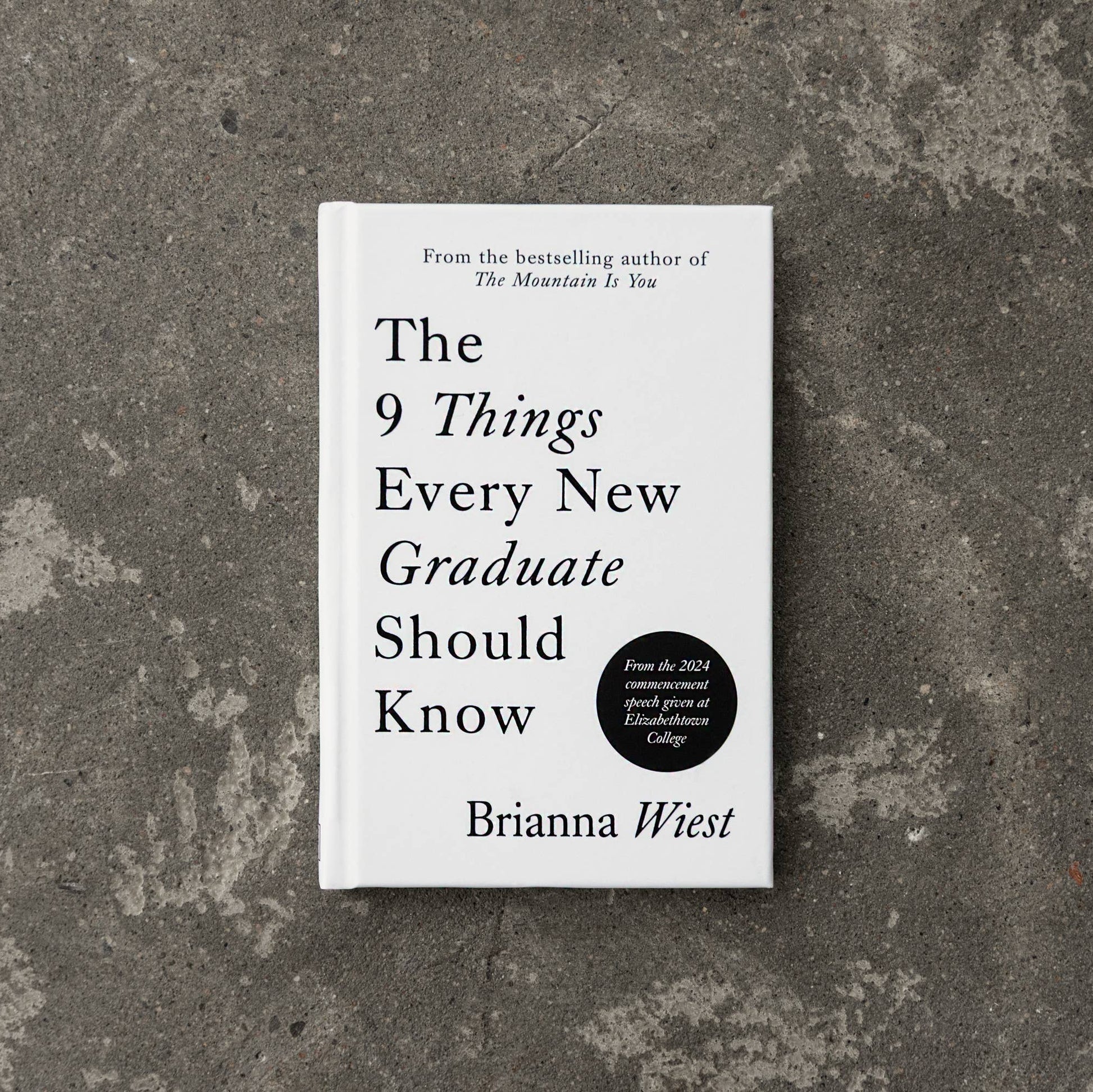 Book titled 'The 9 Things Every New Graduate Should Know' by Brianna Wiest on a textured gray surface