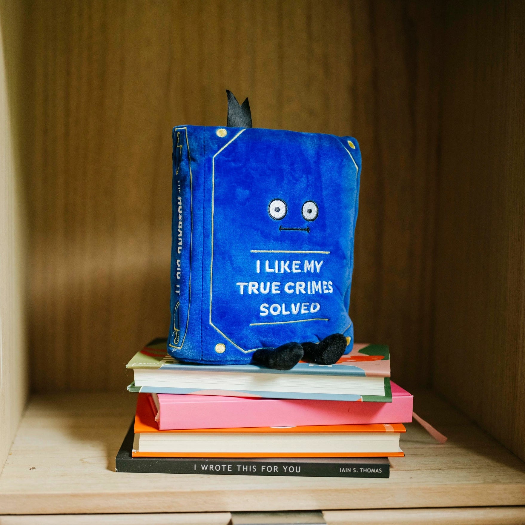 Blue plush toy with a book on a wooden shelf