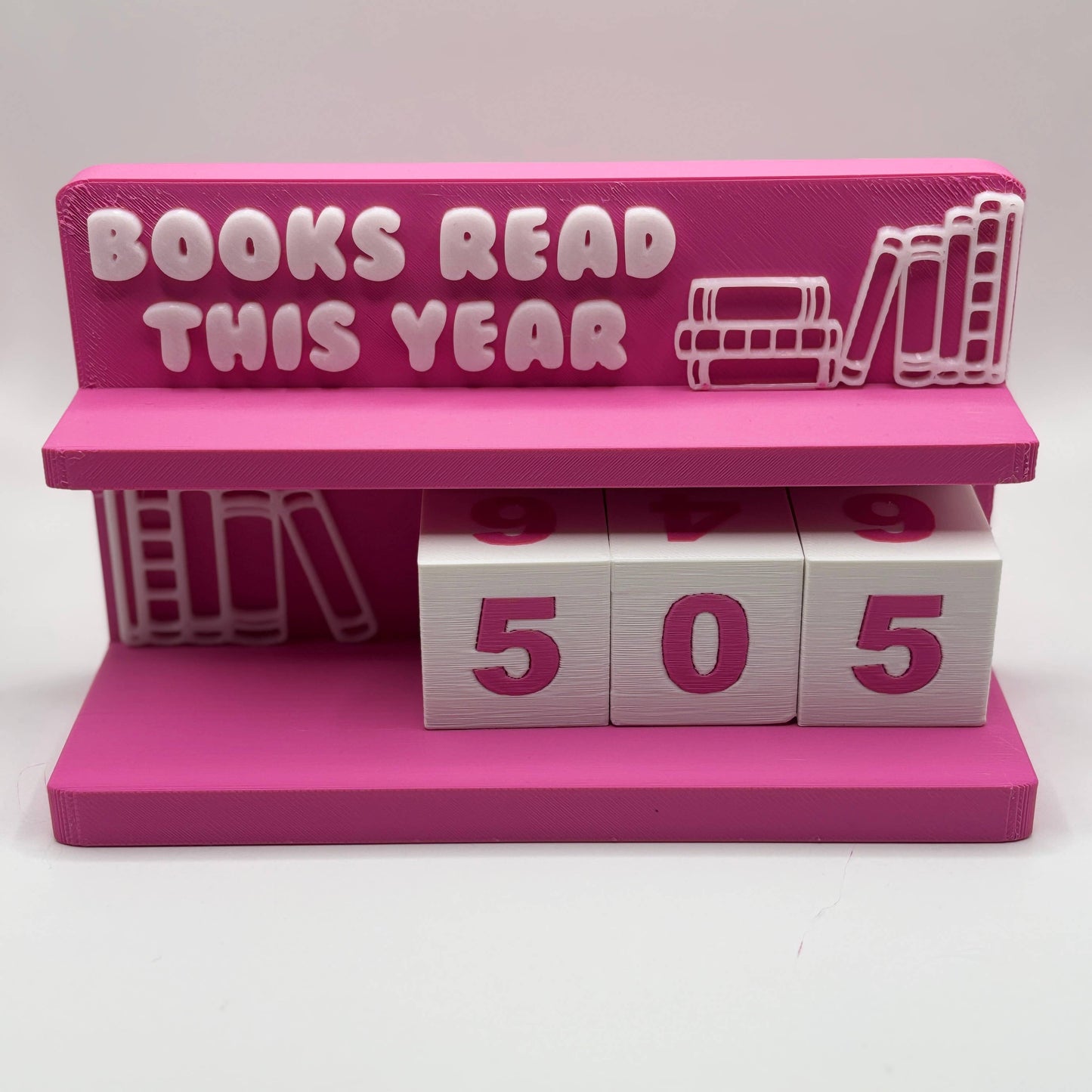 Pink holder with 'Books Read This Year' text and number blocks showing 505 on a white background