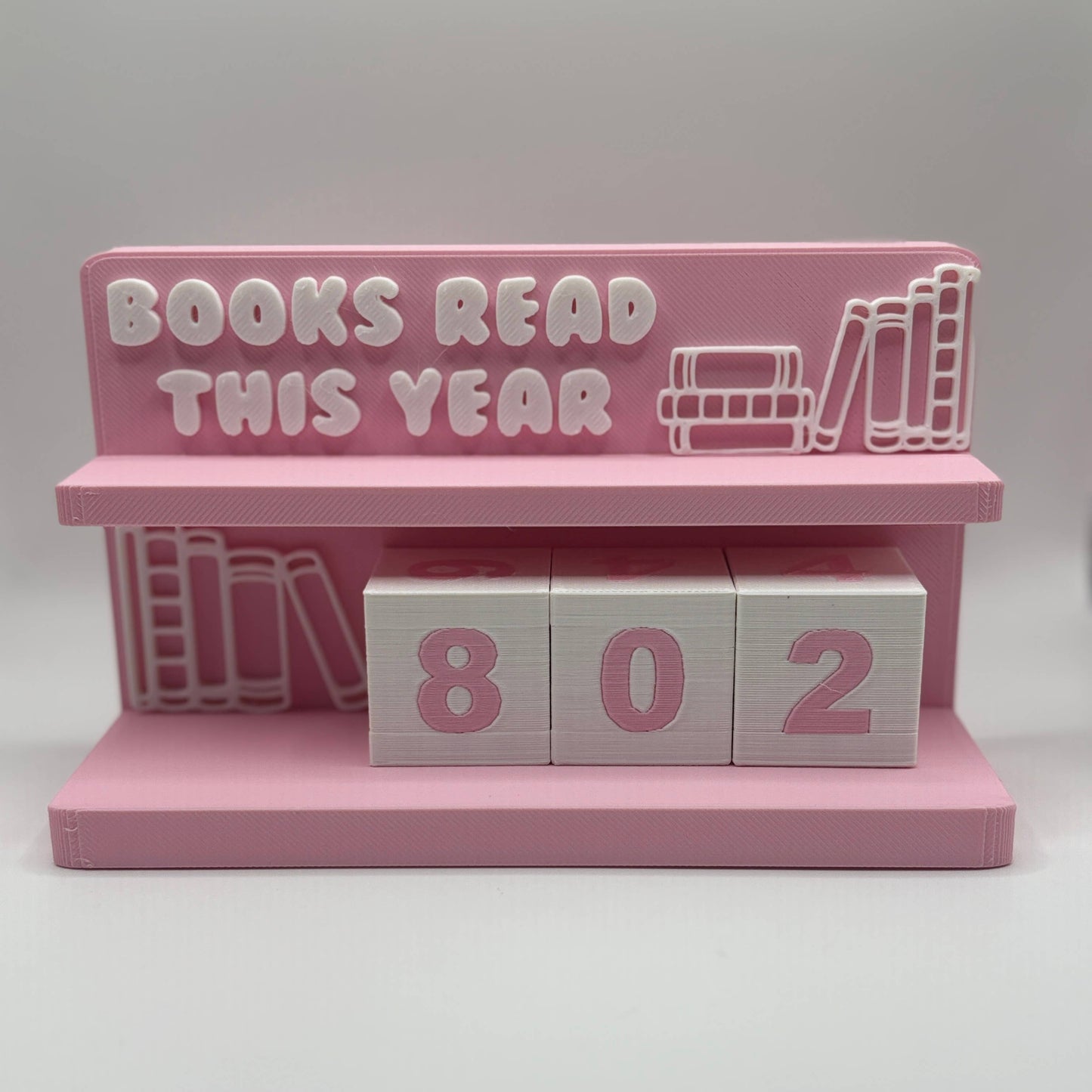 Pink bookshelf with 'Books Read This Year' text and wooden blocks displaying '802'.