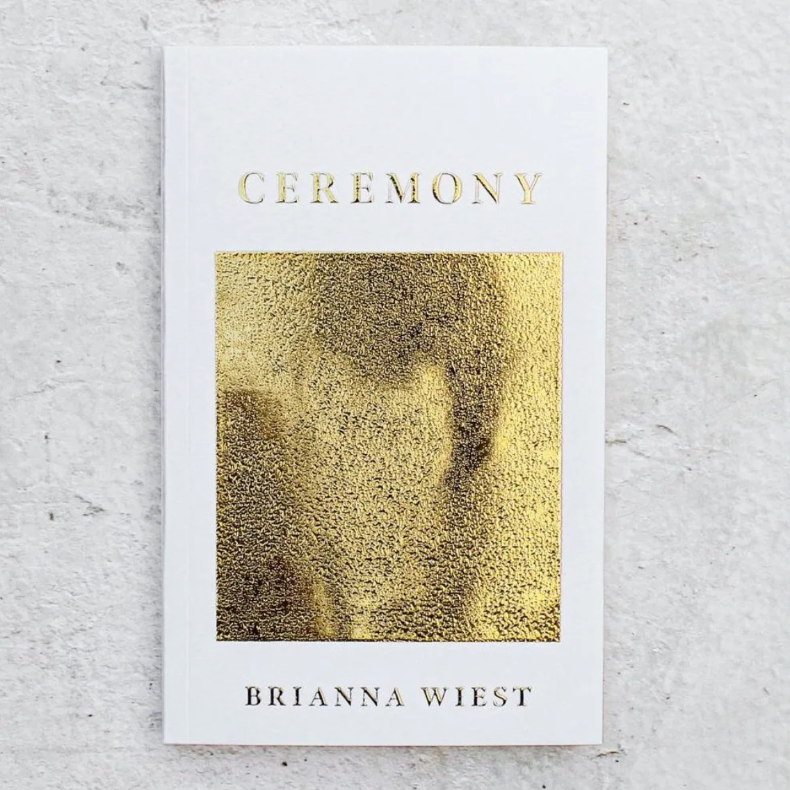 Book titled 'Ceremony' by Brianna Wiest with gold cover on a light gray background
