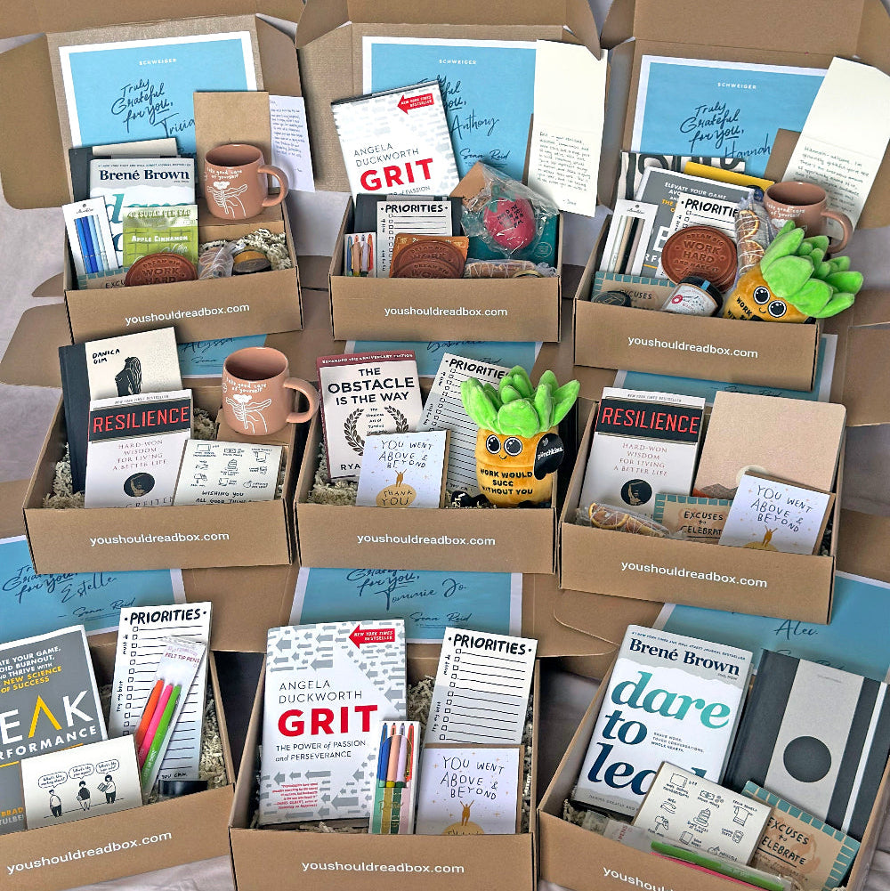 Collection of boxes containing various items like books, mugs, and stationery on a neutral background