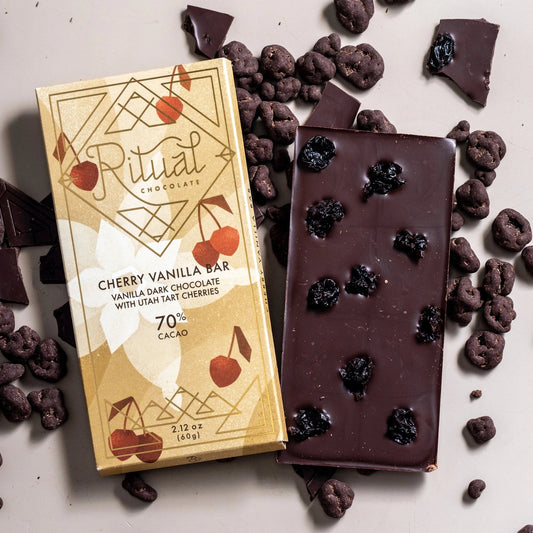 Ritual chocolate bar with packaging surrounded by dark chocolate pieces on a light background