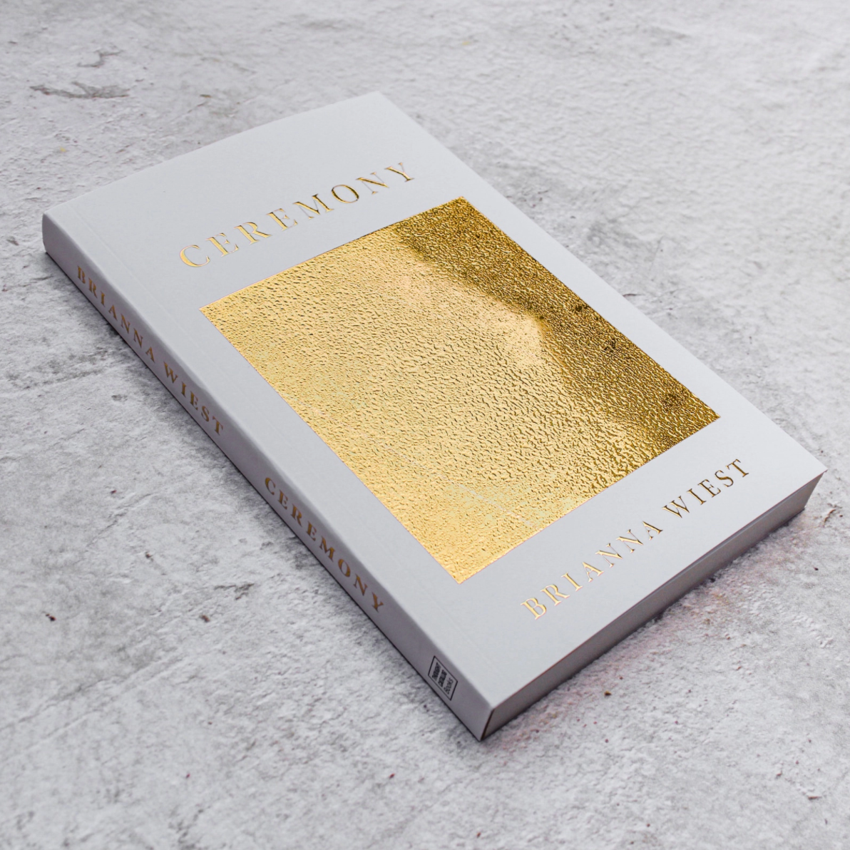 Book with gold cover and gray spine on a textured surface
