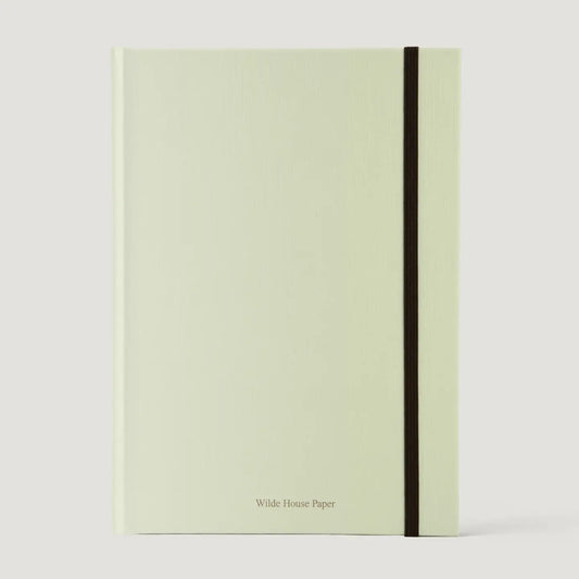A pale sage green hardcover notebook with a black elastic closure band and 'Wilde House Paper' printed in small black text at the bottom, shown on a light gray background.