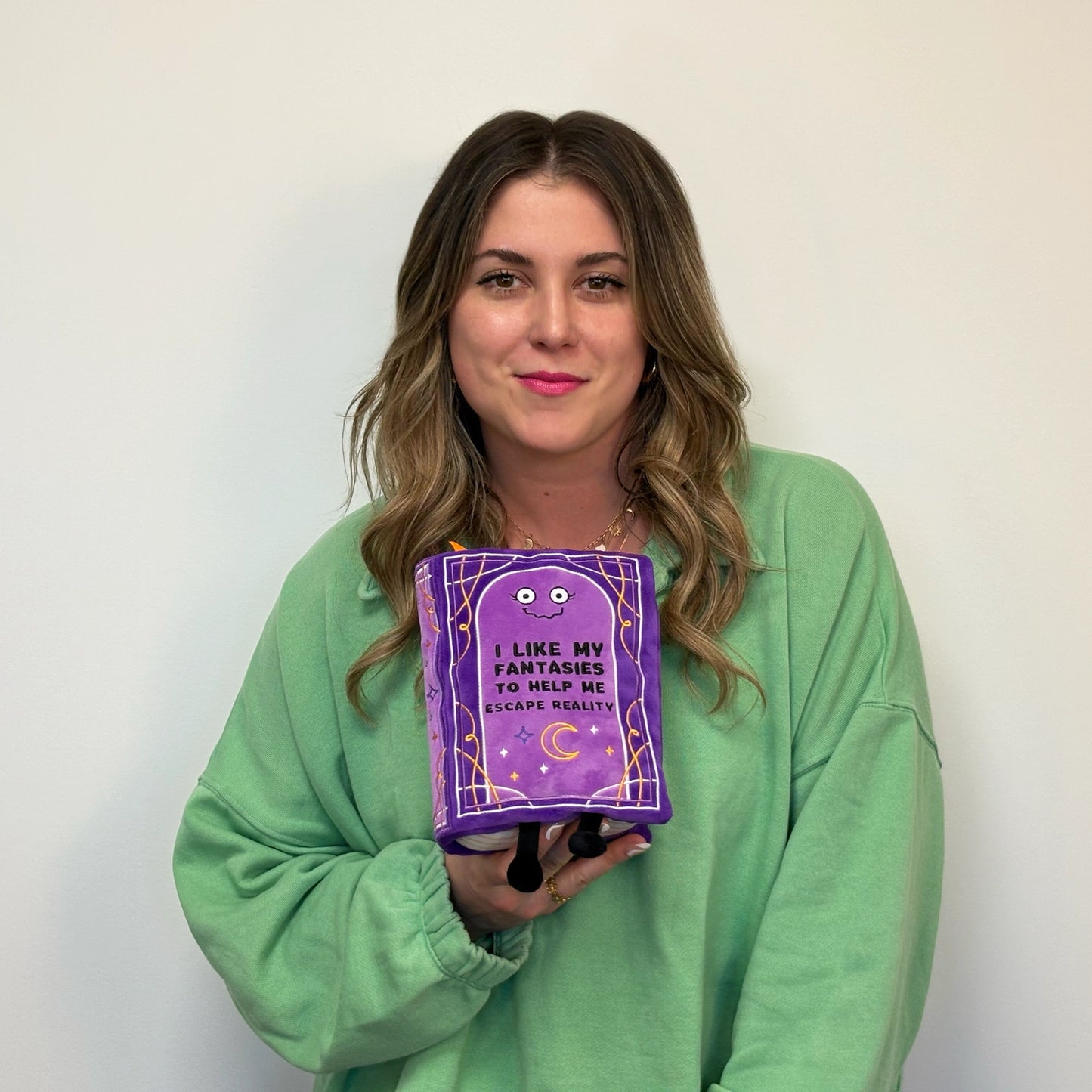 Woman holding a purple book with text against a plain background